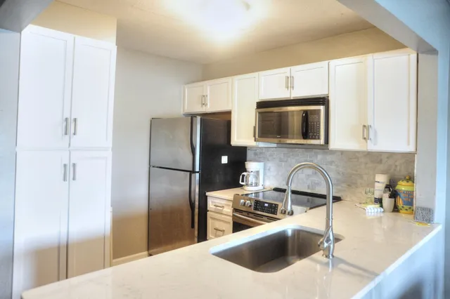 a kitchen with stainless steel appliances kitchen island granite countertop a refrigerator a sink a stove a microwave and wooden cabinets