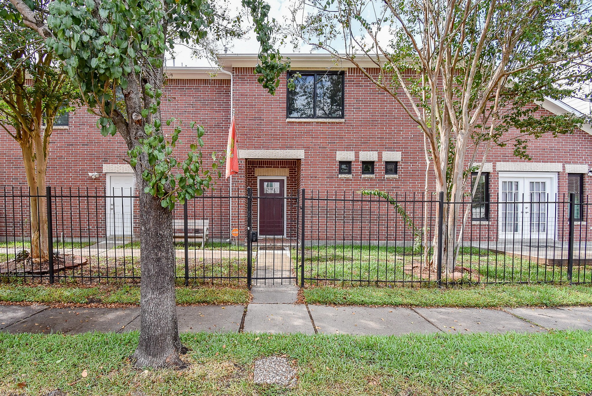a view of a brick house in front of a yard and plants