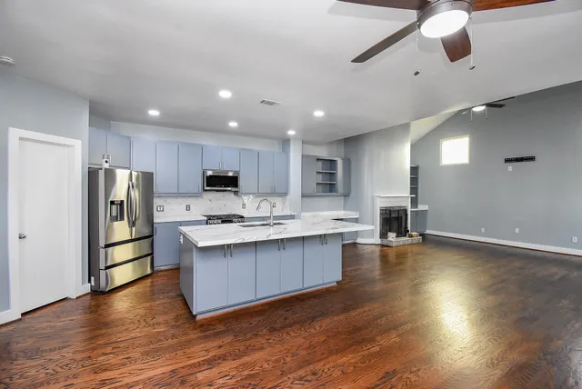 a kitchen with stainless steel appliances granite countertop a refrigerator a sink dishwasher a stove and a wooden floors