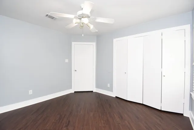 an empty room with wooden floor and fan