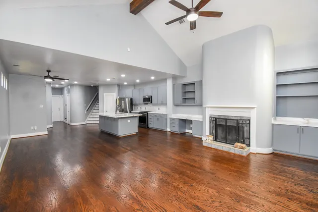 a view of a kitchen with a stove a fireplace a ceiling fan and wooden floor