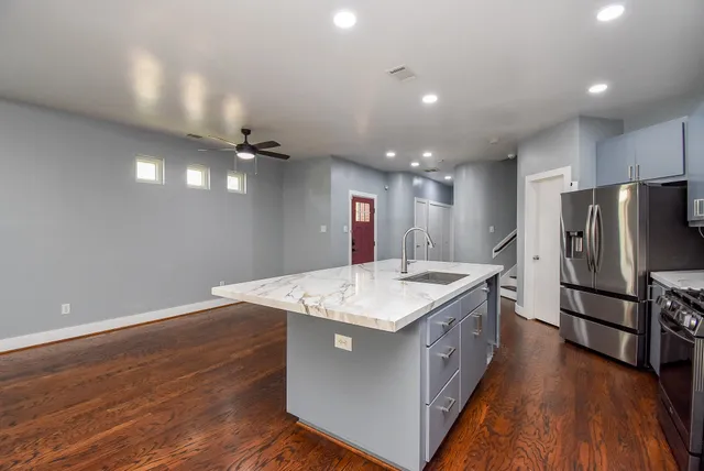 a kitchen with a sink stainless steel appliances a refrigerator and wooden floor