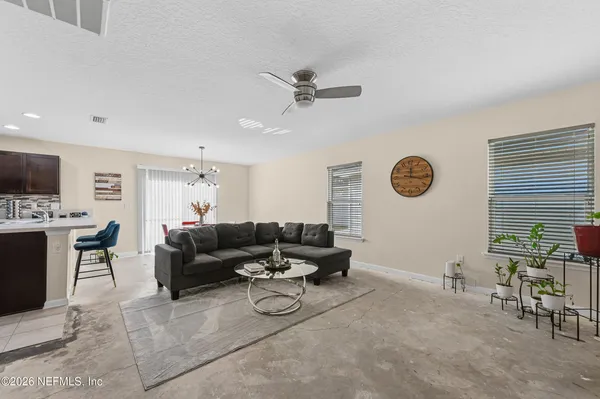a living room with furniture kitchen view and a chandelier
