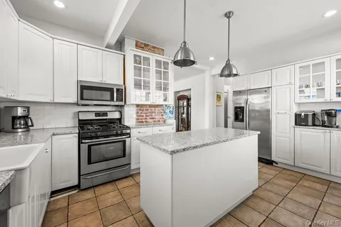 a kitchen with stainless steel appliances granite countertop a sink a stove a refrigerator and cabinets