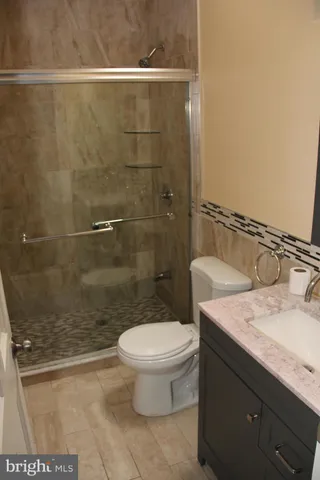 a bathroom with a granite countertop sink a toilet and a shower