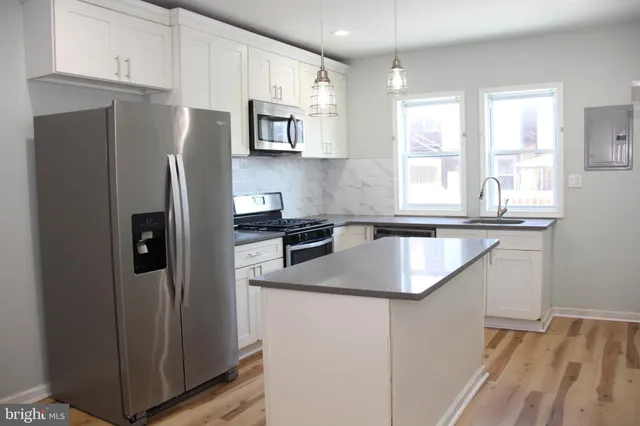 a kitchen with stainless steel appliances granite countertop a refrigerator a sink a stove a microwave and island