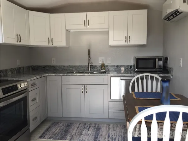 a kitchen with stainless steel appliances granite countertop a stove a sink and a microwave