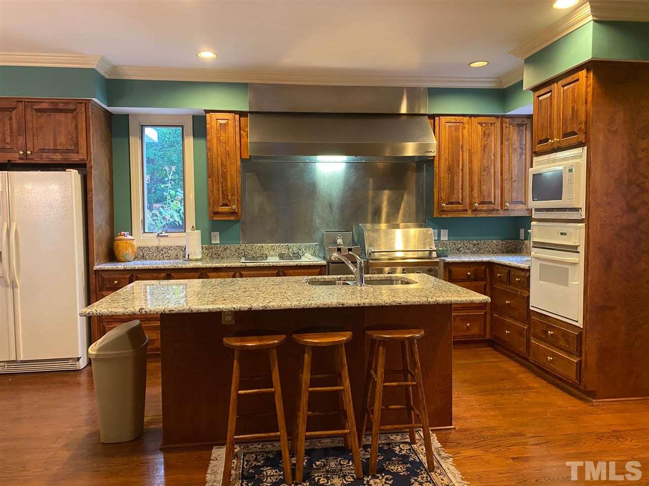 3904 Hemsbury Way Raleigh, NC 27612 - Photo 10 of 20 a kitchen with kitchen island granite countertop wooden cabinets and refrigerator