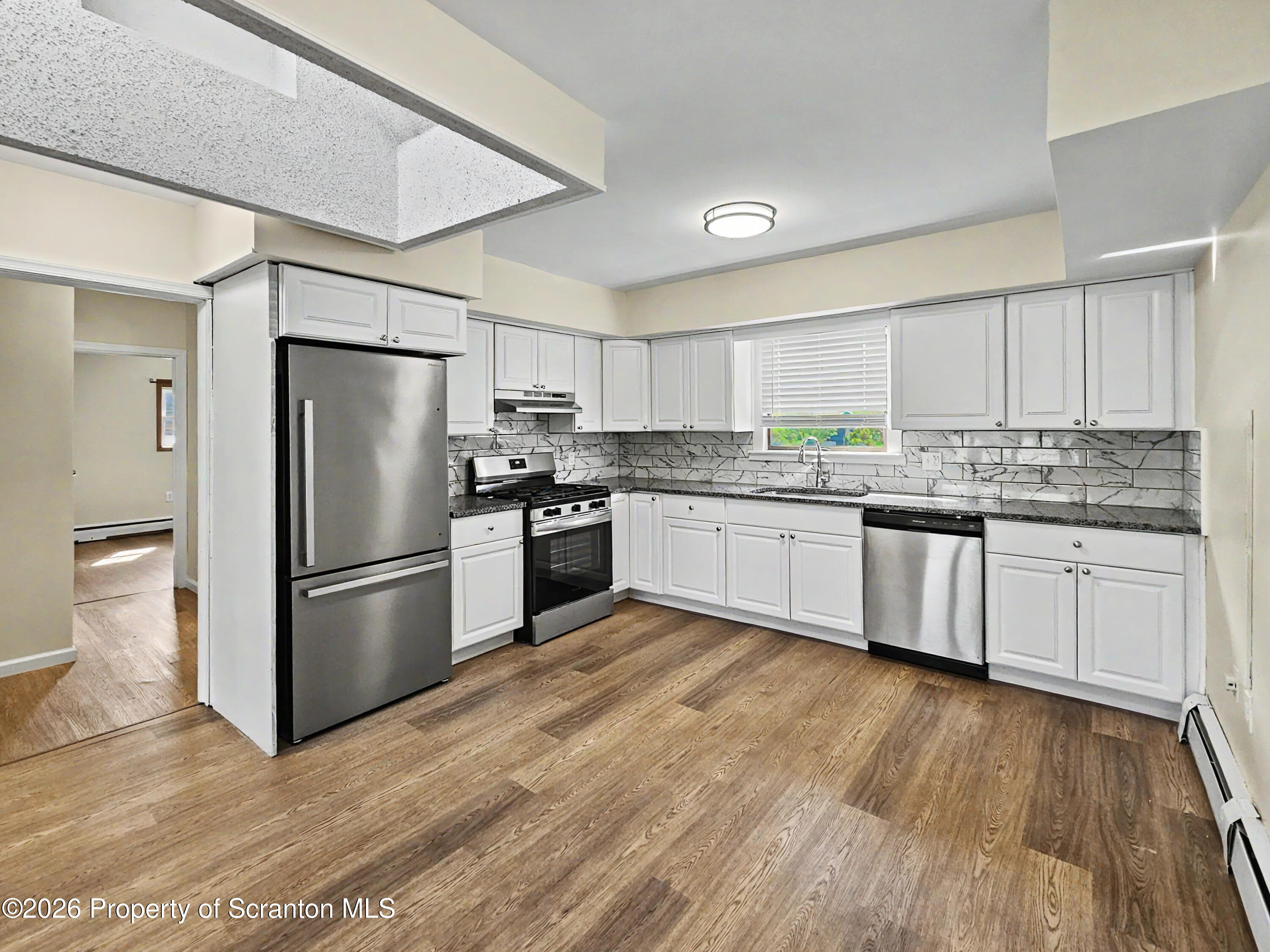 134 Lampman Street Avoca, PA 18641 - Photo 2 of 22 a kitchen with stainless steel appliances granite countertop a refrigerator a sink dishwasher a stove top oven a refrigerator with white cabinets and wooden floor