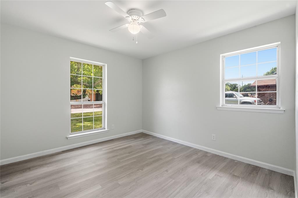 837 Springdale Road Bedford, TX 76021 - Photo 14 of 28 Spacious room featuring light gray walls, wood-finish flooring, and multiple windows with white trim