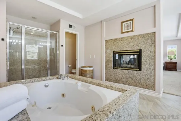 a large spacious bathroom with a granite countertop tub shower and mirror