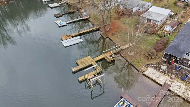a view of a lake with a chairs and table on wooden deck