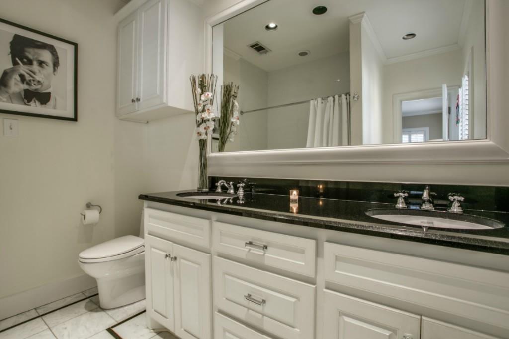 5419 Merrimac Avenue Dallas, TX 75206 - Photo 7 of 17 Dual vanity with a black countertop and undermount sinks, complemented by white cabinetry with polished chrome hardware