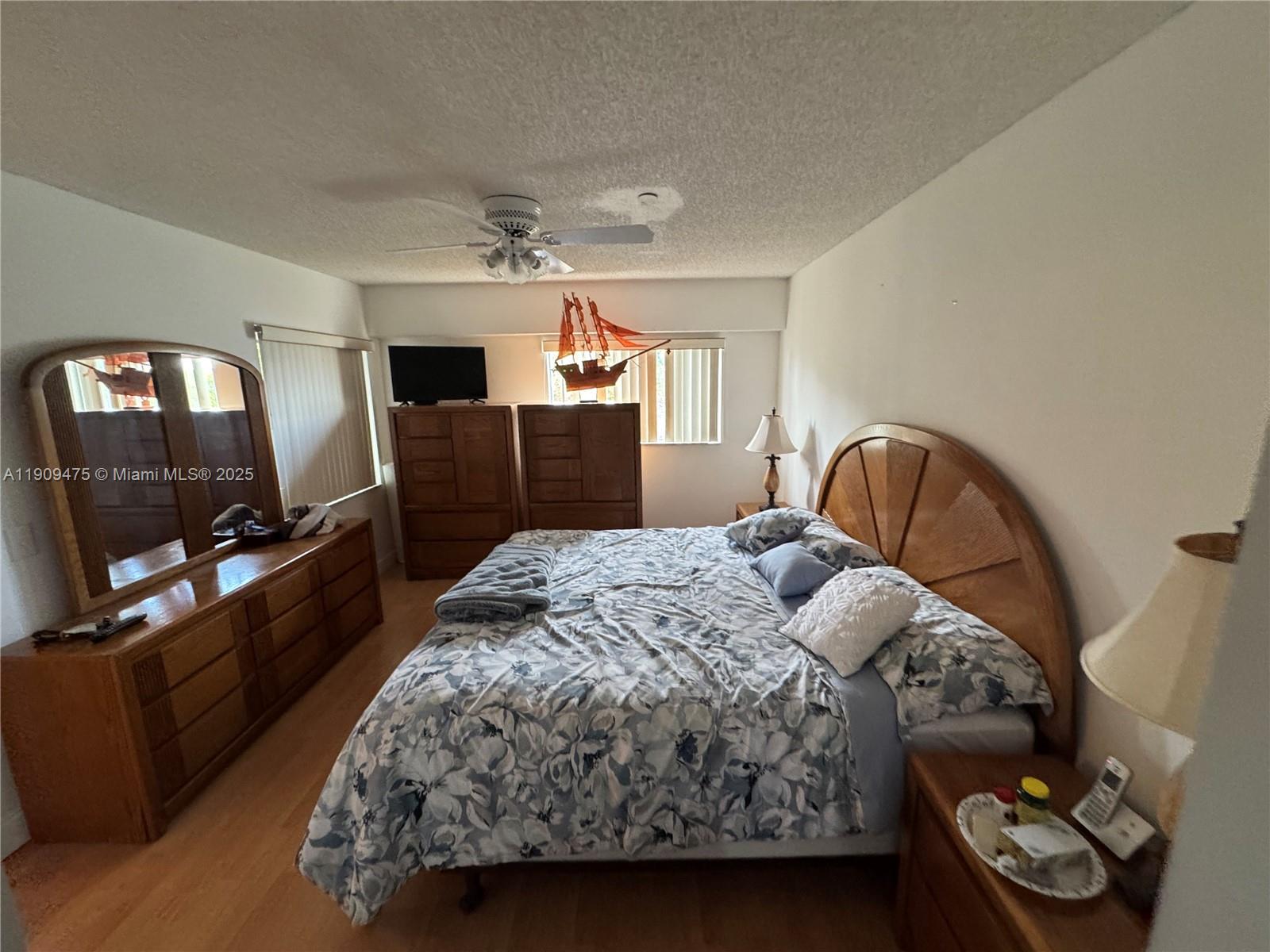 1650 Southwest 124th Terrace, Unit 403D Pembroke Pines, FL 33027 - Photo 8 of 11 a bedroom with a bed a mirror on dresser and a chandelier