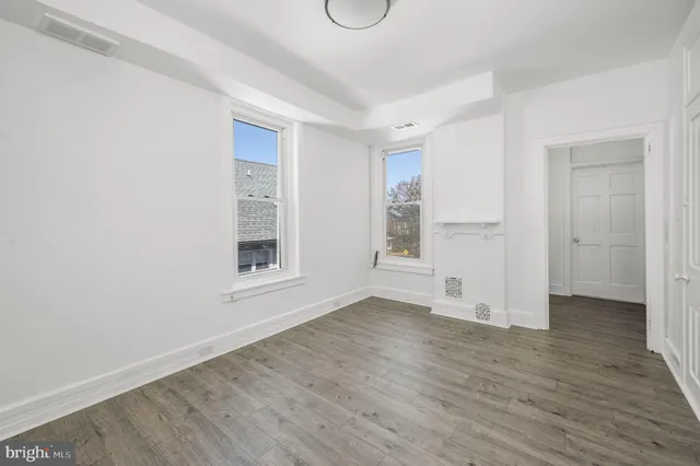 a view of an empty room with wooden floor and window