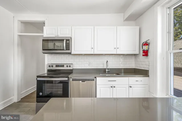 a kitchen with cabinets stainless steel appliances and a window