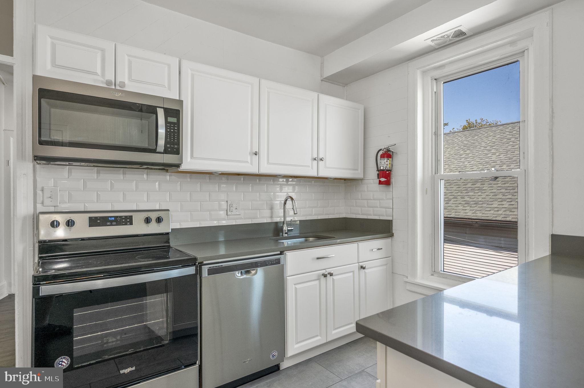 303 South Main Street, Unit 2 Phoenixville, PA 19460 - Photo 7 of 24 a kitchen with stainless steel appliances granite countertop a stove microwave and cabinets