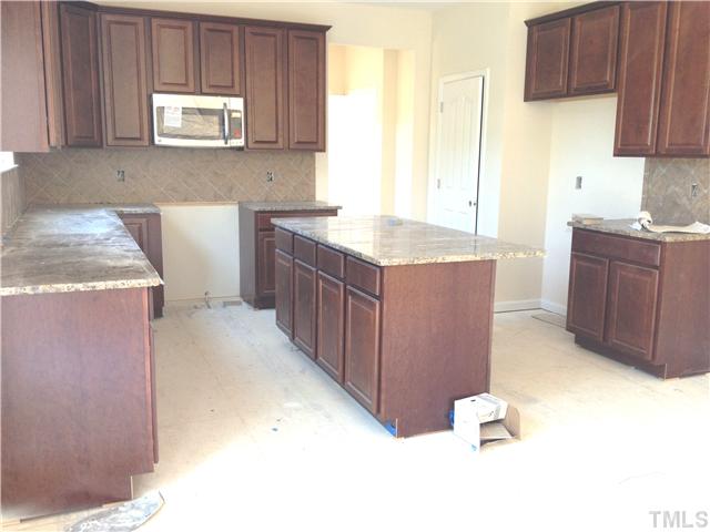1104 Farmers Branch Road Willow Spring, NC 27592 - Photo 2 of 16 a kitchen with kitchen island granite countertop wooden cabinets a sink and dishwasher