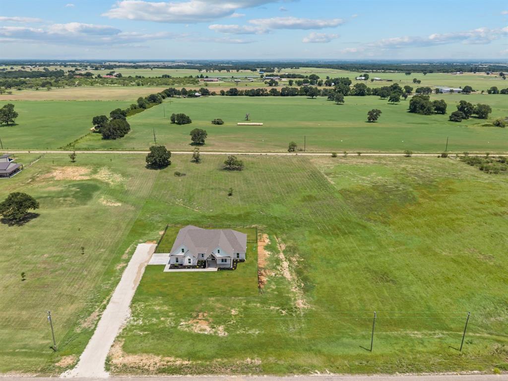 2705 Gospel Road Tolar, TX 76476 - Photo 3 of 36 New construction home on an expansive green lot, featuring a grey roof, light-colored siding, an attached garage, and a long gravel driveway