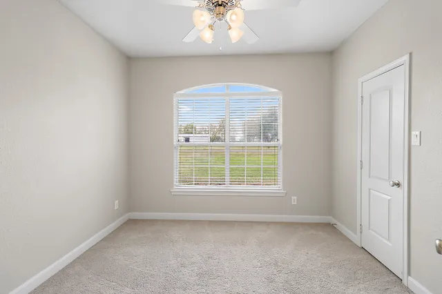 an empty room with windows and ceiling fan