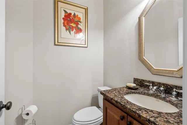 a bathroom with a granite countertop toilet sink and mirror