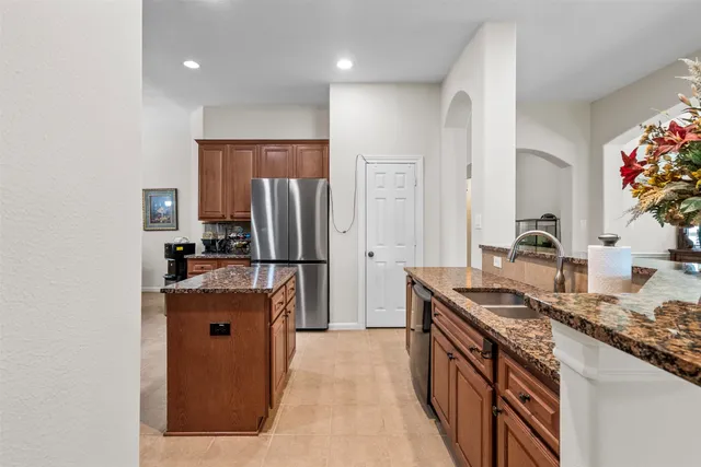 a kitchen with stainless steel appliances granite countertop a refrigerator a stove and a sink