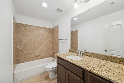 a bathroom with a granite countertop sink a toilet and shower