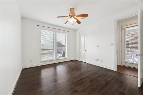 an empty room with wooden floor chandelier fan and windows