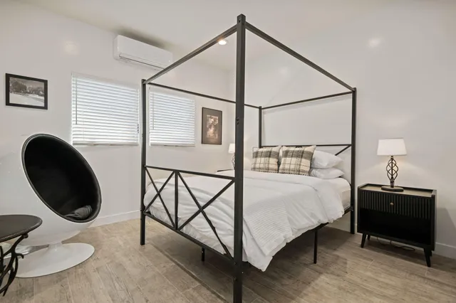 a bedroom with a bed and a potted plant on the dresser