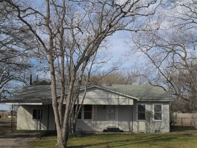 a front view of a house with a garden and tree