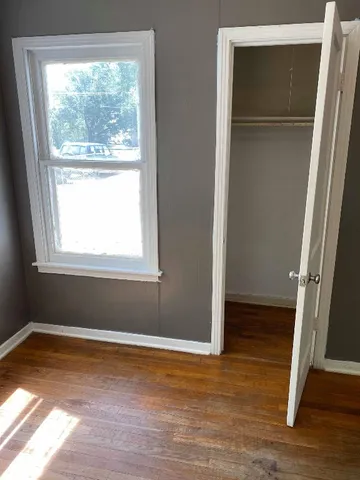 a view of empty room with wooden floor and fan