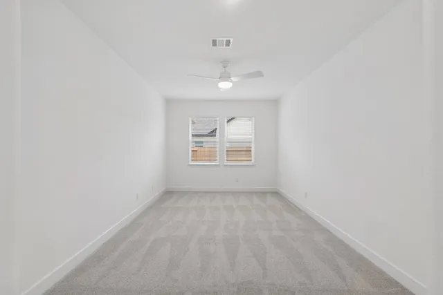 an empty room with windows and ceiling fan