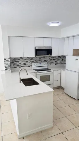 a kitchen with a sink a stove top oven and white kitchen
