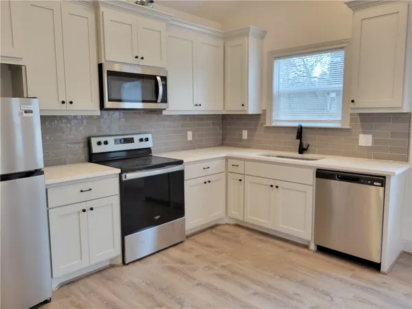 a kitchen with white cabinets white stainless steel appliances and sink