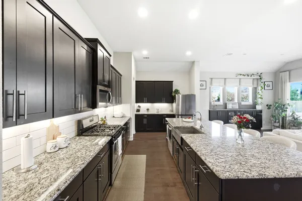 a large living room with stainless steel appliances granite countertop couches a flat screen tv and a view of kitchen