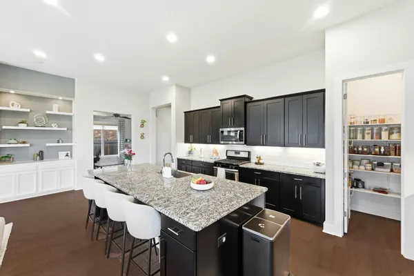a kitchen with granite countertop kitchen island stainless steel appliances a sink and counter space