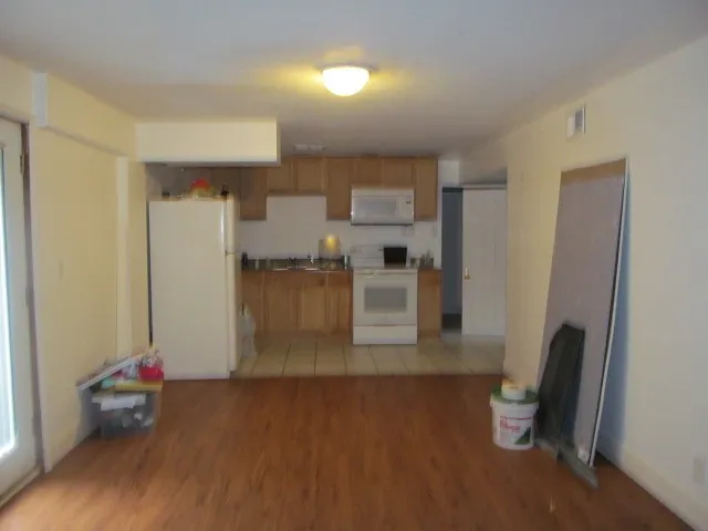 a view of a kitchen with refrigerator and wooden floor