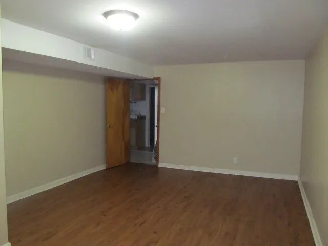 an empty room with wooden floor and natural light