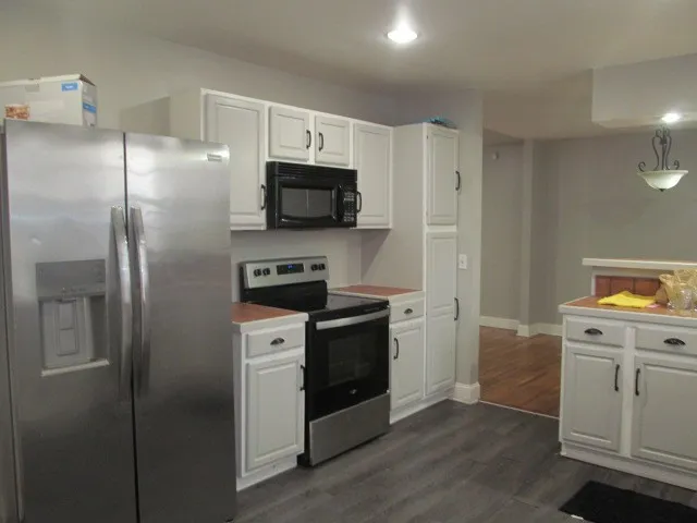 a kitchen with a refrigerator stove and white cabinets