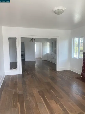 an empty room with wooden floor fireplace and windows