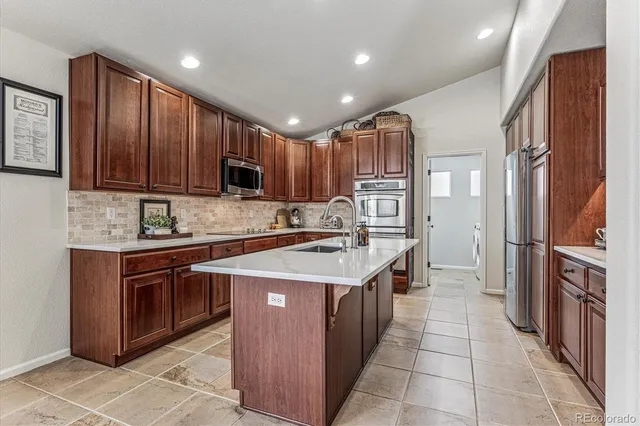 a kitchen with stainless steel appliances granite countertop a stove top oven a sink and a refrigerator