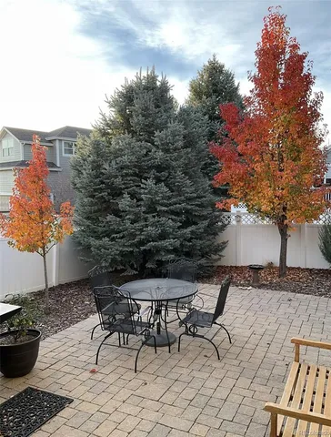 a patio with table and chairs and potted plants
