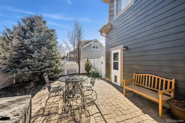 a view of a patio with a table and chairs and wooden fence