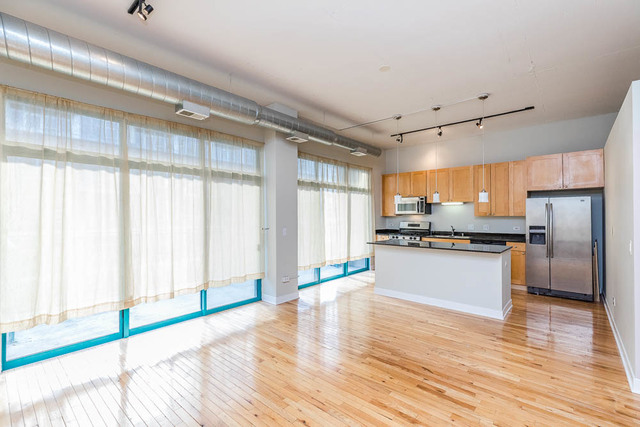 910 West Madison Street, Unit 703 Chicago, IL 60607 - Photo 5 of 23 a kitchen with stainless steel appliances wooden floor and large window