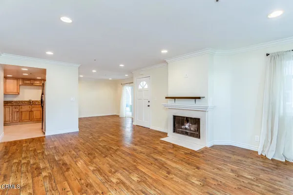 a view of an empty room with wooden floor fireplace and a window
