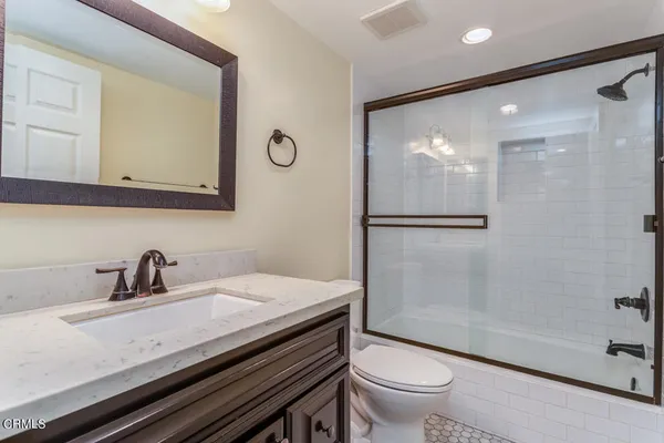 a bathroom with a granite countertop sink a toilet a mirror and shower