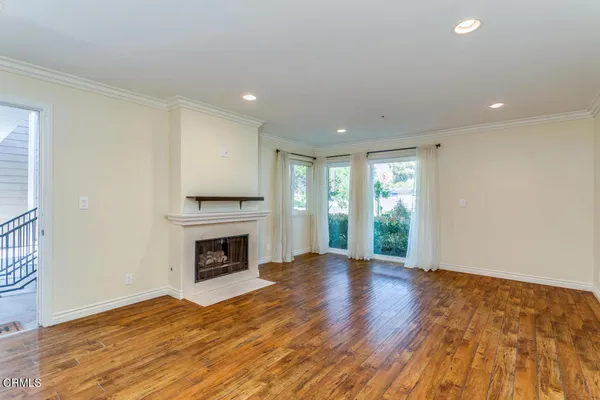 a view of an empty room with wooden floor fireplace and a window