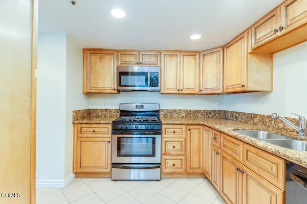 a kitchen with stainless steel appliances granite countertop a stove a sink and a microwave