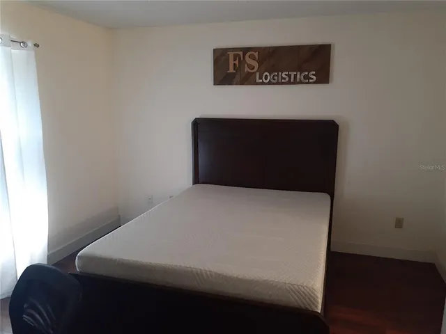 a bed sitting in a bedroom next to a window with wooden floor