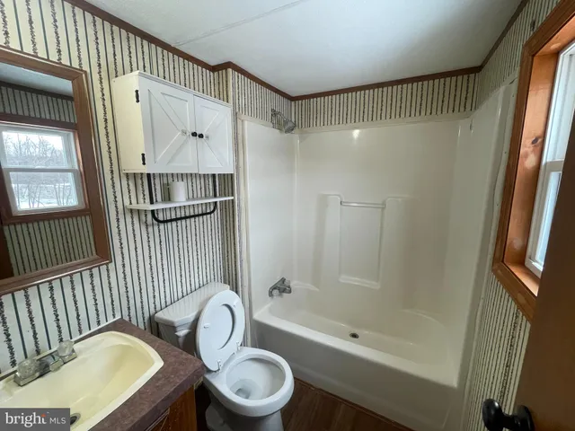 a bathroom with a toilet sink a mirror and shower